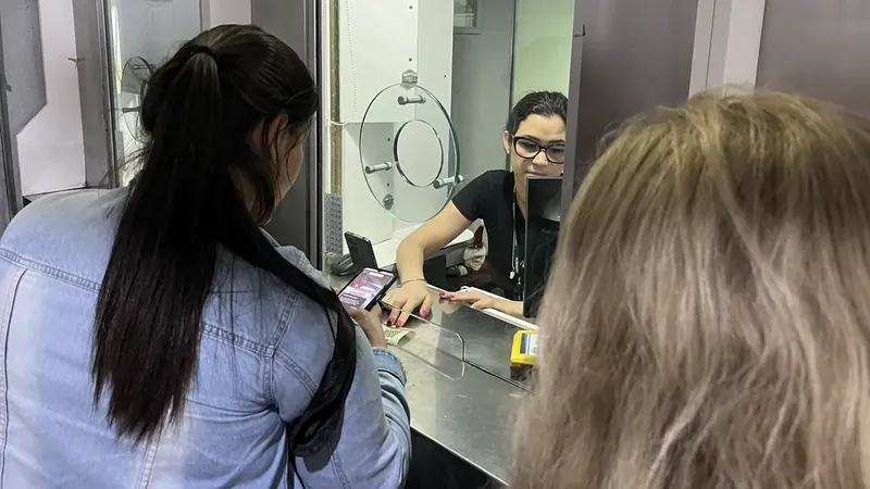 Passageira usa o celular diante de uma atendente na bilheteria da Trensurb, durante testes de pagamento por Pix.