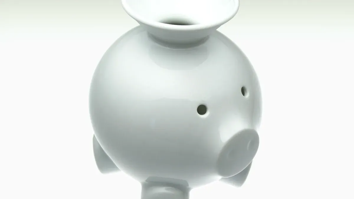 A close-up of a white ceramic piggy bank with a funnel-shaped coin opening against a pale background.