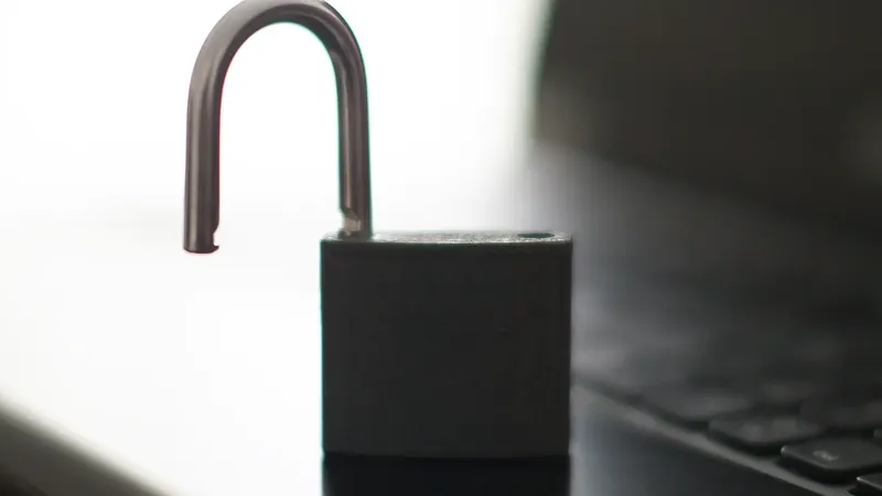 An open black padlock beside a laptop keyboard, photographed with a shallow depth of field.